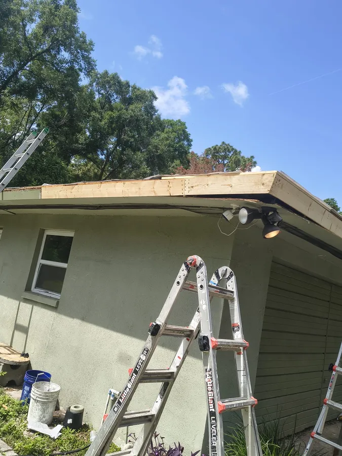 State Certified Roofing crew with ladders repairing fascia and roof edge on site